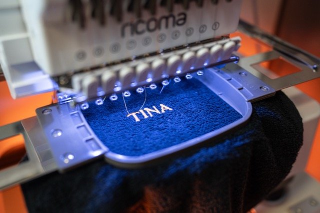 Borduurresultaat — naam TINA op blauwe handdoek